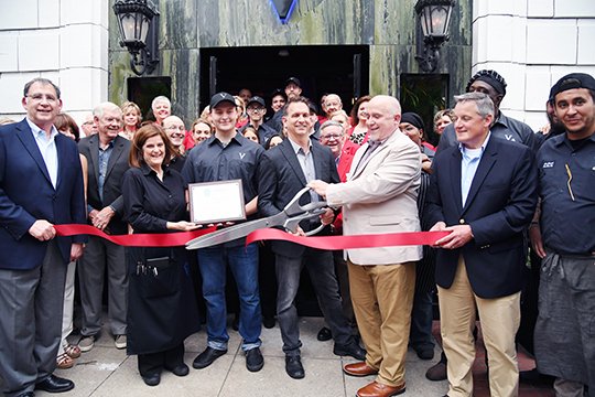 The Sentinel-Record/Grace Brown NEW BUSINESS: On Thursday, Vault co-owner Dr. Daron Praetzel, center, left, and General Manager Randy Womack cut the ribbon on Vault, the 100th business to open in the downtown are since the fire that destroyed the Majestic Hotel in 2014.