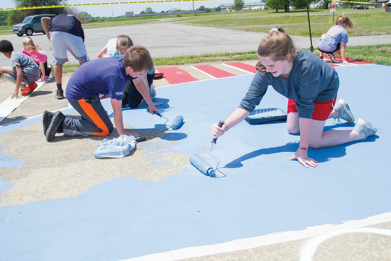 Harding Academy students Jack Thomas and Sabrina Rampey, along with Brylee Jeffrey, behind Thomas, paint the inside of the 3-point line on an outdoor court at the Searcy Event Center.