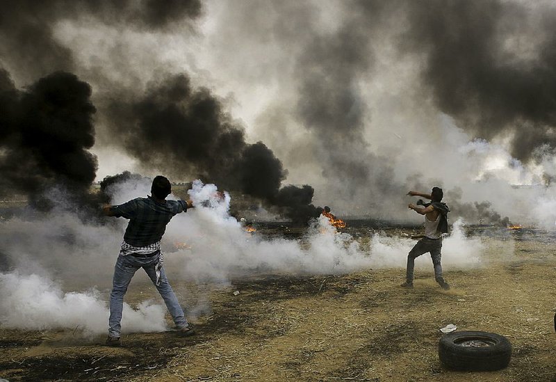 Palestinian protesters throw back tear-gas canisters at Israeli soldiers after they burned tires Friday near the fence at the Gaza Strip’s border with Israel.  
