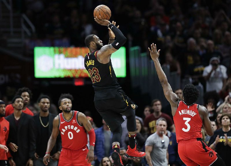 Cleveland Cavaliers forward LeBron James (left) hits the game-winning shot as Toronto Raptors guard OG Anunoby defends Saturday in Cleveland. The Cavaliers defeated the Raptors 105-103.  