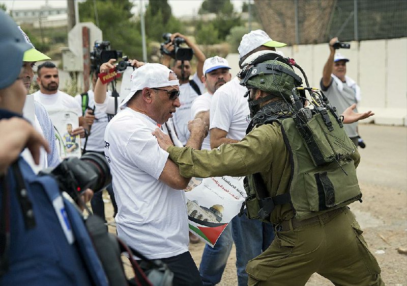 An Israeli soldier scuffles with a man during a protest Sunday in front of the Beit El Israeli army checkpoint near the West Bank city of Ramallah. The Palestinian Journalists Syndicate organized the protest after two Palestinian journalists were killed during recent clashes at the Gaza border. 