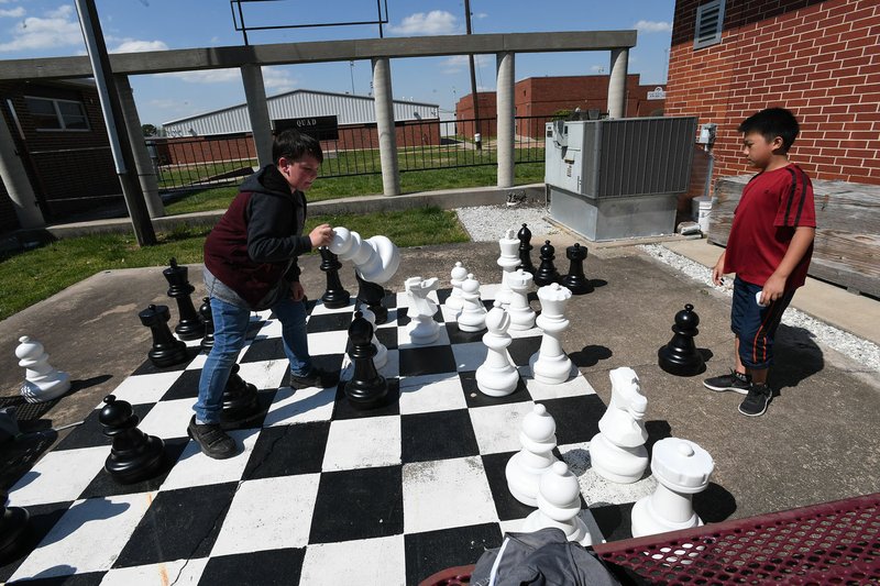 Bryce Bradley makes a move while playing with Nathan Lee on April 30 at the Lincoln Middle School chess club. The club has set up several outside boards as well as one oversized board. The Lincoln students recently won the Scholastic State Chess Championship in the K-8 division for the second straight year and will represent Arkansas at the national championships in Wisconsin this summer. 