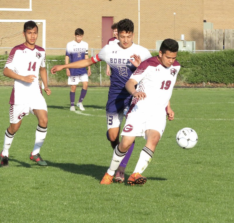 Westside Eagle Observer/RANDY MOLL Ramon Arguijo, a Gentry junior, moves the ball away from a Berryville defender during the April 30 game at Gentry High School. Behind him is Gentry's Giovanny Ramirez.