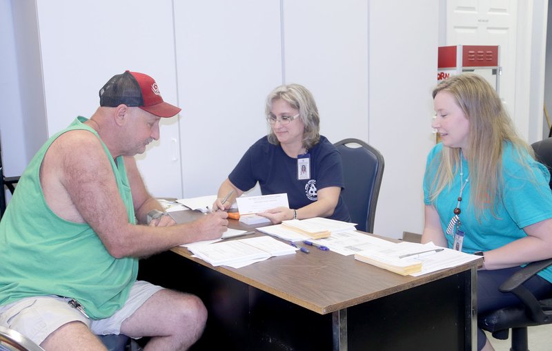 LYNN KUTTER ENTERPRISE-LEADER Jackie Apple of Lincoln signs up to receive fresh produce through farmers' markets in the area with Lisa McClelland and Casey Pruitt, both representatives with Area Agency on Aging of Northwest Arkansas.