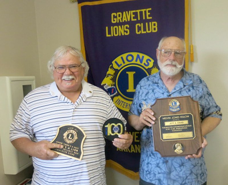 Westside Eagle Observer/SUSAN HOLLAND Bill Mattler, Gravette Lions Club president, and Jeff Davis, club secretary-treasurer, display awards won by the Gravette club at the 100th Arkansas Lions state convention April 27 and 28 in Conway. Mattler holds the Legacy Award bronze plaque for the club's mural and foosball projects and a patch denoting the club had at least 15 new members during the centennial challenge. Davis displays the plaque he received after being designated a Melvin Jones Fellow.