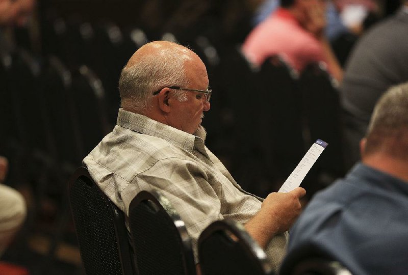Terry Moseley of Benton looks over the list of candidates scheduled to speak Wednesday at the Farm Bureau Measure the Candidate event in North Little Rock.  
