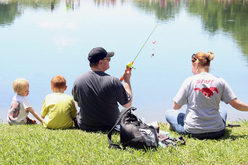 MEGAN DAVIS MCDONALD COUNTY PRESS/Southwest City's fishing derby is a family affair, as made evident by these parents last year, who loaded the bait, and their children, who cast the lines.
