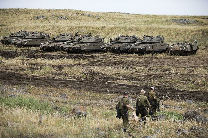 Israeli soldiers walk Thursday near tanks parked in the Israeli-controlled Golan Heights, near the border with Syria. 