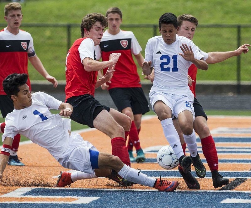 Willie Hernandez (1) of Rogers kicks the ball toward the net Thursday while teammate Nelson Rivas (21) tries to maintain his position during the Mounties’ 6-0 victory over Cabot in the Class 7A boys soccer state tournament at Gates Stadium in Rogers. 