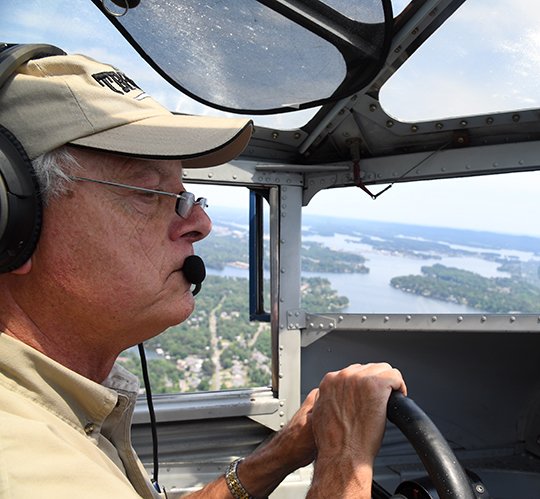 The Sentinel-Record/Grace Brown HIGH VISIBILITY: Pilot Bill Sleeper guides a 1929 Ford Tri-Motor airplane over Lake Hamilton during a special media flight on Thursday. The Experimental Aircraft Association is giving tours and rides in the aircraft through Sunday.