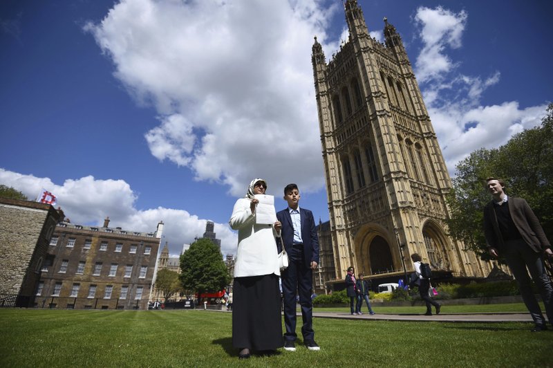 Fatima Boudchar and her 14-year old son Abderrahim Belhaj, stand outside the Houses of Parliament in London, Thursday May 10, 2018. Britain's Attorney General Jeremy Wright told lawmakers that Prime Minister Theresa May had apologized "unreservedly" to Abdel Hakim Belhaj and his wife Fatima Boudchar, acknowledging that Britain's actions "contributed to your detention, rendition and suffering." (Kirsty O'Connor/PA via AP)