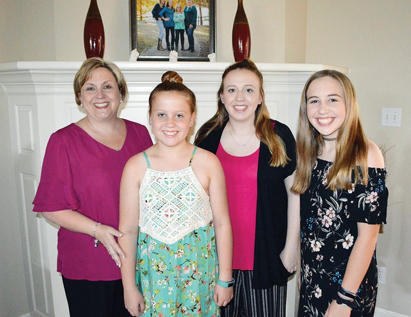 Mandy McClellan stands with her three daughters in their Conway home. From left, her daughter Sophie is 11, Abby is 17, and Keely is 13. The two older girls have cochlear implants, and McClellan co-founded Arkansas Hands & Voices about 10 years ago to help other parents of children with hearing loss. “They’re just normal kids,” she said of her daughters.