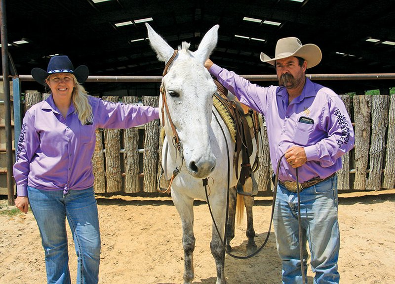 Jennifer Bailey and her husband, Mark Bailey, stand outside with their mule, Woodrow, in front of the arena at Whiskey Ridge Ranch. The ranch will host Racing on the Ridge, which will begin Thursday. The chuck-wagon races will be from 
1-4 p.m. Saturday and Sunday.