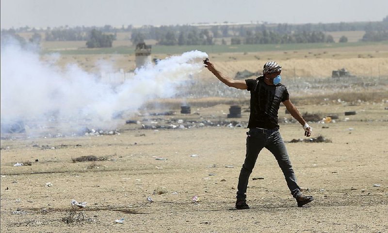 A Palestinian protester carries a tear-gas canister that was fired across the border into the Gaza Strip by Israeli soldiers during clashes Friday. 
