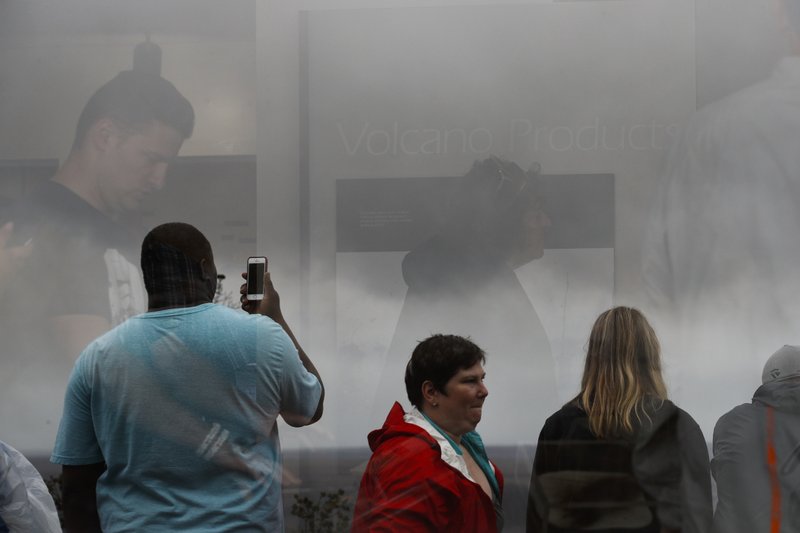 Visitors are reflected in the window of the Jaggar Museum as they view Kilauea's summit crater in Volcanoes National Park, Hawaii, Thursday, May 10, 2018. The park is closing Friday due to the threat of an explosive volcanic eruption. (AP Photo/Jae C. Hong)