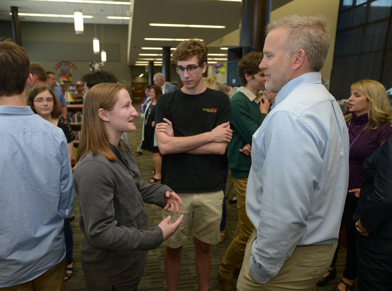 NWA Democrat-Gazette/ANDY SHUPE Fayetteville High School senior Cesca Craig (left) speaks Thursday with Nate Magre (right), an advance placement history teacher, alongside her friend Ethan Favorite, a student at the University of Arkansas, during an academic signing ceremony in the Matthew Moore Library at the school. Craig plans to attend New York University and study anthropology.