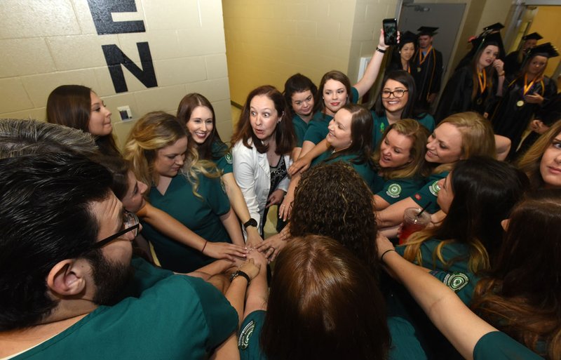 NWA Democrat-Gazette/FLIP PUTTHOFF Faith Paine (center), an instructor with the NWACC nursing program, leads nursing graduates Saturday in a cheer before the grads lined up for commencement.