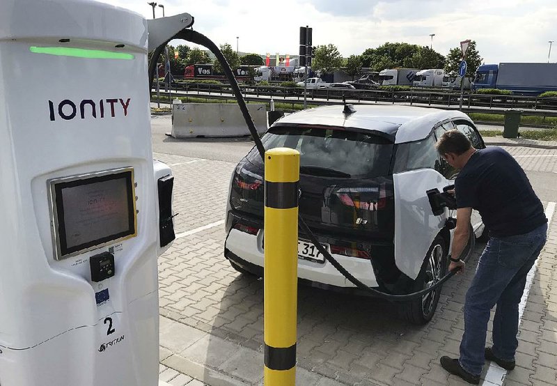 A man charges his BMW electric vehicle Friday at a rest stop in Niederzissen, Germany. The fastcharging station for electric vehicles is run by Ionity, a joint venture of several automakers. 
