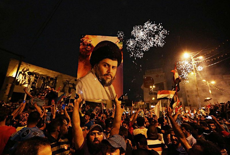 Supporters of Shiite cleric Muqtada al-Sadr carry his image in Baghdad’s Tahrir Square as they celebrate partial election returns Monday. 
