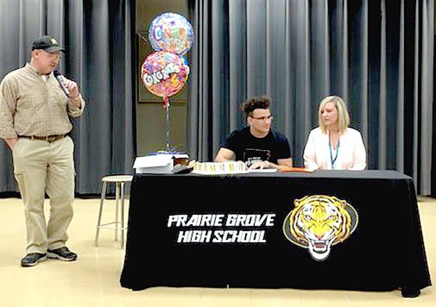 Submitted photo Prairie Grove senior Anthony Johnson (center) signs a national letter of intent to play college football for Hendrix College, of Conway, on Monday, April 23. Johnson was accompanied by his mother, Andrea Harrell (right) and Prairie Grove head football coach Danny Abshier. Johnson earned All-State and All-Conference honors leading the Tigers in rushing as a senior.