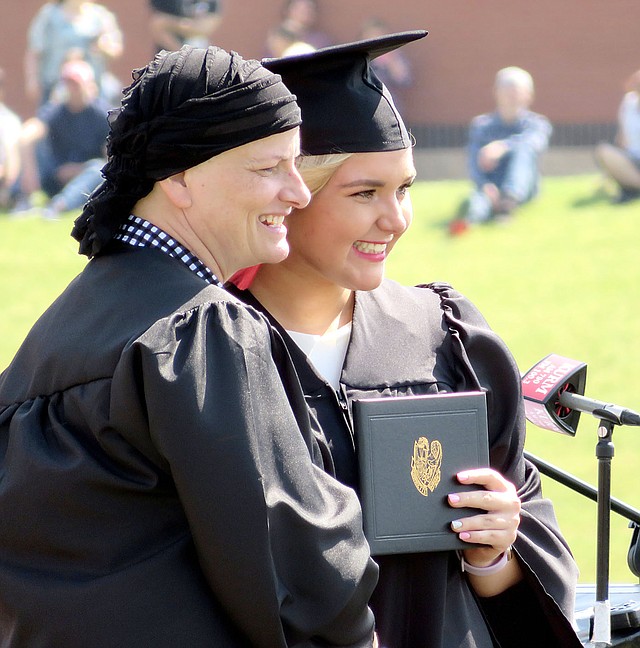 Westside Eagle Observer/RANDY MOLL Kaitlyn Loyd poses for a photo with class sponsor and teacher Carla Hicks after receiving her diploma at Gravette graduation ceremonies on Saturday, April 12, 2018.