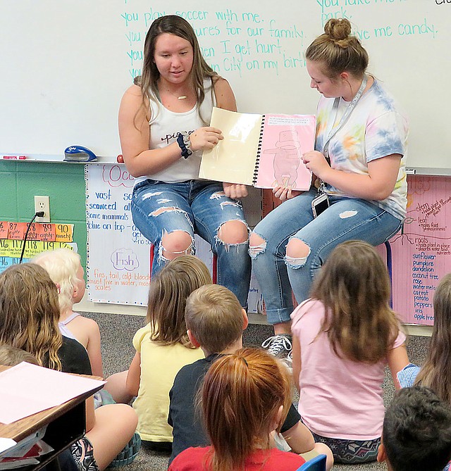 Westside Eagle Observer/RANDY MOLL Madi Boyd (left) and AnnDee Holt read a book they wrote to first-grade students at Gentry Primary School on Friday. Pre-AP English II students from Gentry High School wrote children's books for their end-of-the-year project and then read them to first-grade classes at the primary school.