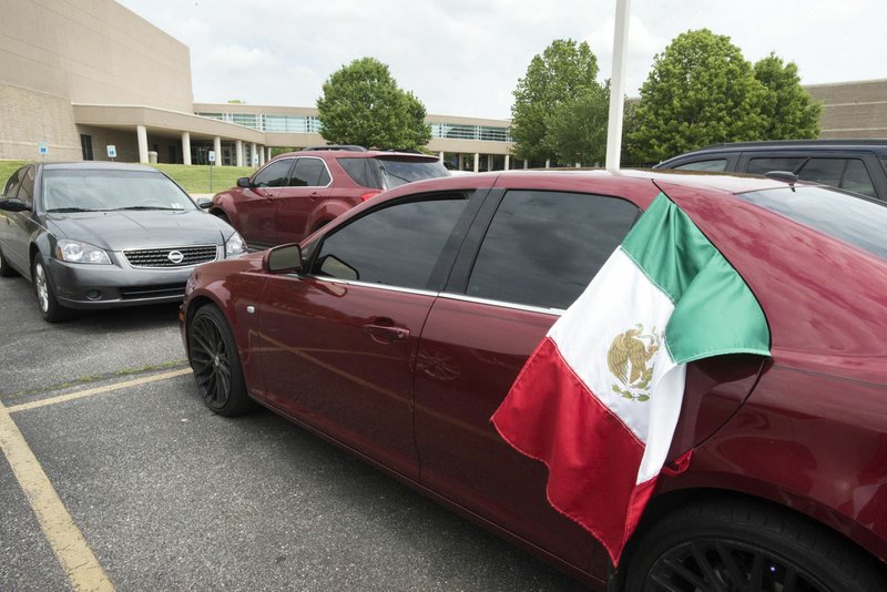 NWA Democrat-Gazette/CHARLIE KAIJO A Mexican flag hangs from the window of a parked car Monday in the parking lot at Rogers High School.