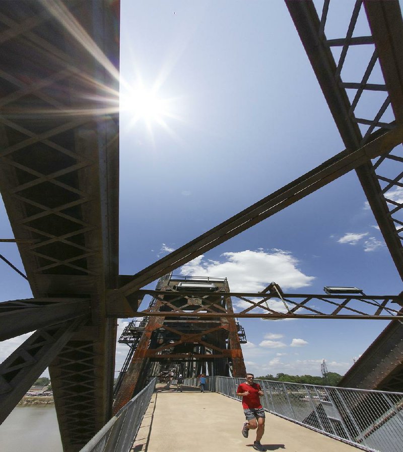 Arkansas Democrat-Gazette/JOHN SYKES JR. -  A jogger crosses the Clinton Presidential Park Bridge in Little Rock Wednesday, May 16, braving warm temperatures that reached into the 90s in central Arkansas.