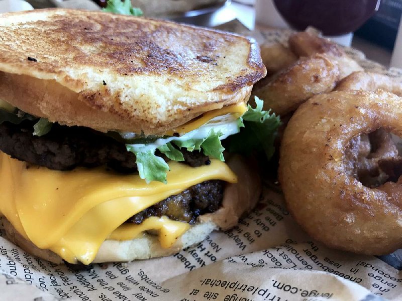 The Cheeeesy burger, served here with onion rings, has not just four “Es” but four slices of cheese at Wayback Burgers in Little Rock.