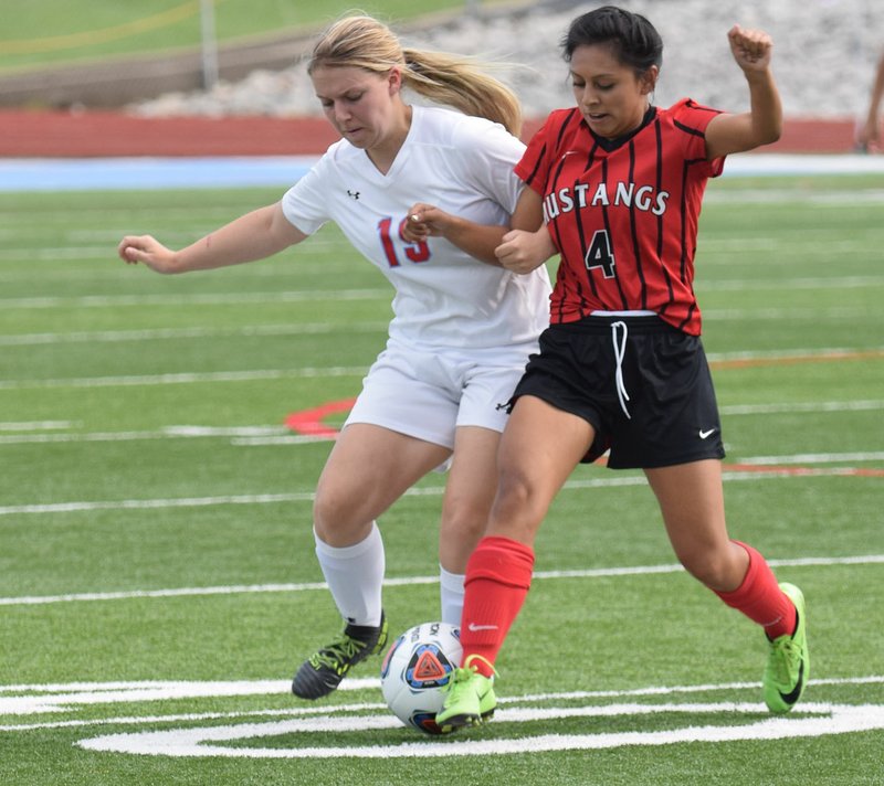 RICK PECK/SPECIAL TO MCDONALD COUNTY PRESS McDonald County's Karen Gasca (4) and Webb City's McKenzie Brown fight for control of a loose ball during the Lady Cardinals' 7-0 win on Monday night in the district soccer tournament at Webb City High School.