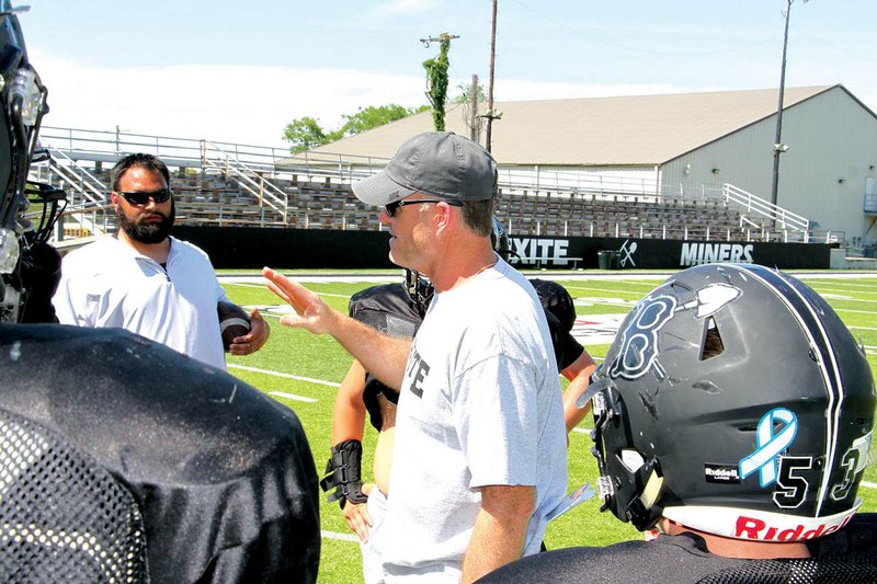 Offensive line coach Paul Calley, center, talks to members of the Bauxite Miners football team during a practice May 14. Also shown is defensive line coach Tommy Wimberly. Calley was recently hired as an assistant principal for Bauxite Middle School but will also serve on the staff for the football team under head coach Daryl Patton. 