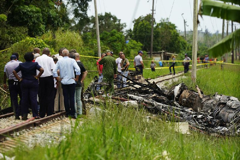 Rescue workers gather Friday at the site near the Havana airport where a Cuban airliner plummeted into a cassava field and caught fire.  