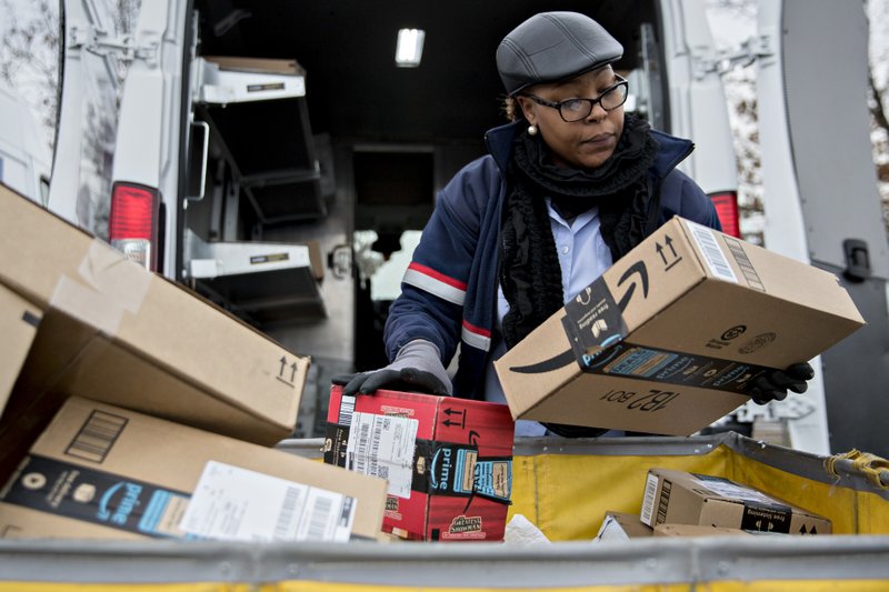 A letter carrier holds Amazon.com Inc. packages while preparing a vehicle for deliveries at the United States Postal Service Joseph Curseen Jr. and Thomas Morris Jr. processing and distribution center in Washington. 