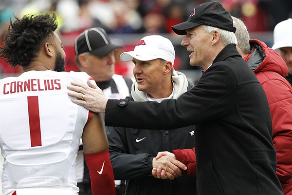 Arkansas wide receiver Jared Cornelius (1) and head coach Chad Morris shake hands with Arkansas Gov. Asa Hutchinson after the coin toss before the Razorbacks' Red-White football game on Saturday, April 7, 2018, at War Memorial Stadium in Little Rock.
