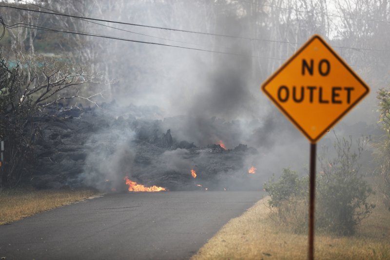 Lava crosses the road near Pohoiki Rd, Friday, May 18, 2018, near Pahoa, Hawaii. Hawaii residents covered their faces with masks after a volcano menacing the Big Island for weeks exploded, sending a mixture of pulverized rock, glass and crystal into the air in its strongest eruption of sandlike ash in days. (AP Photo/Marco Garcia)
