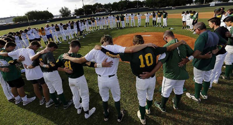 Members of the Santa Fe High School baseball team join playoff rivals of Kingwood Park High for a prayer Saturday around the pitcher’s mound before their game in Deer Park, Texas. 