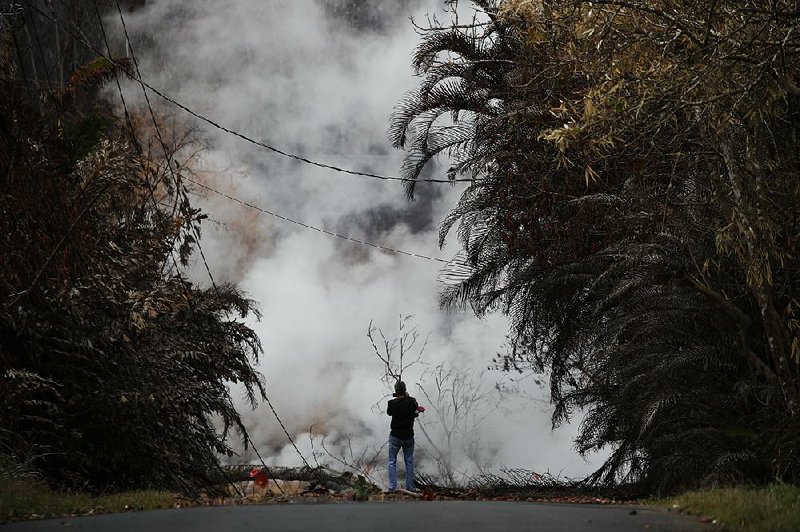A resident photographs toxic gases rising from cracks in the Leilani Estates subdivision near Pahoa, Hawaii, on Saturday. 
