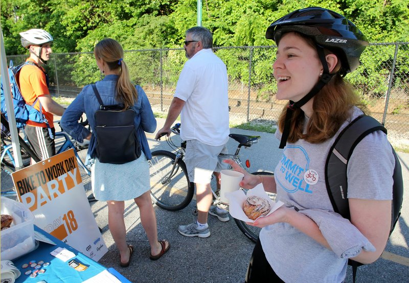 Emily Voight stops for a cup of coffee and a pastry Friday at the Bike NWA Energizer Station set up on the Razorback Greenway at Arsaga’s at The Depot in Fayetteville. Bike NWA was celebrating Bike to Work Day with stations along the Razorback Greenway. May is National Bike Month, sponsored by the League of American Bicyclists, and Friday was National Bike to Work Day. The events are intended to promote the benefits of bicycling and encourage more people to give bicycling a try. Fayetteville and University of Arkansas are partnering to develop a bike share program for the city. 