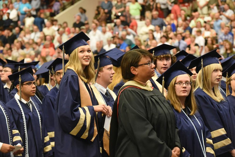 Logan Gibbs (foreground left) scans the audience Saturday as graduates march to their seats for the inaugural graduation ceremony for Bentonville West High School. About 385 graduates took part in the commencement ceremony at Barnhill Arena on the University of Arkansas campus. 