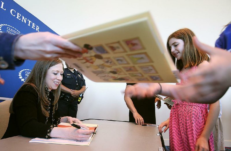 Chelsea Clinton (left) signs a copy of her book, She Persisted Around the World, for Hannah Cherepski (right), 10, after Clinton spoke Sunday at the Statehouse Convention Center in Little Rock. 