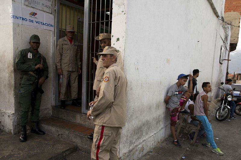 A soldier and members of the Bolivian militia stand guard at the entrance to a polling station during the presidential election in Caracas, Venezuela, on Sunday. 