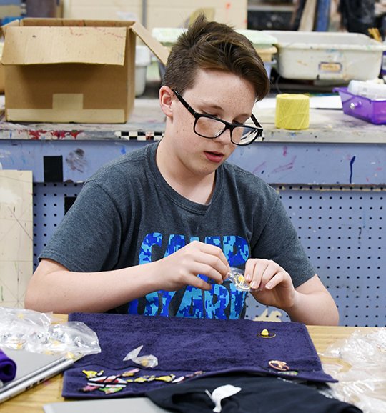 The Sentinel-Record/Grace Brown PIN PREP: Hot Springs Junior Academy student Sandler Moore sorts his supply of Destination Imagination pins on Tuesday, at the school in preparation for his trip to Knoxville, Tenn., to compete in the DI Global Finals.