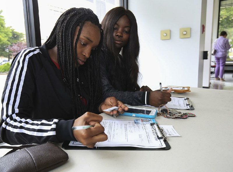 NaTesha Robinson (left), and Khambria Allen fill out early voting request forms Monday at the Pulaski County Regional Building in Little Rock. Monday was the last day of early voting for today’s party primary election and nonpartisan judicial general election. 