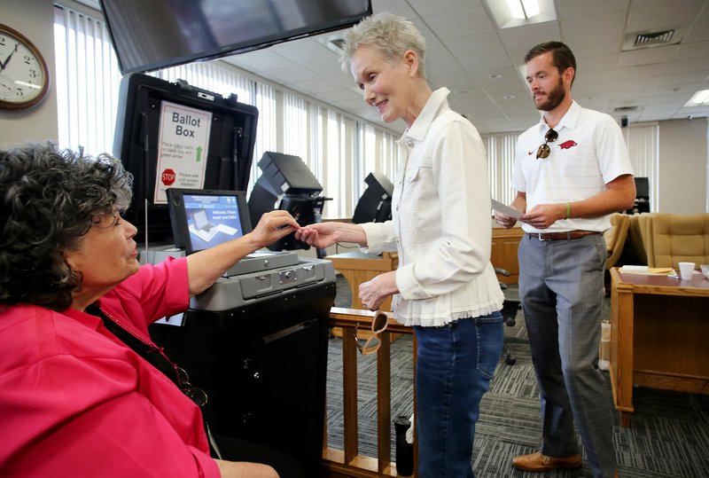 Lana Orman (center) receives a sticker Monday from Martha Hill, Washington County election official, after casting her ballot on the last day of early voting at the Washington County Courthouse in Fayetteville. Voting in the Arkansas primaries is today. 