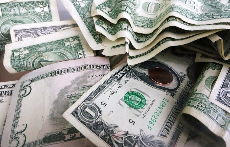 This September 2017 file photo shows a tip jar with one dollar and five dollar bills and a penny in New York. Despite an ultra-low 3.9 percent unemployment rate, about one-third of U.S. adults faced financial insecurity last year and often struggled to pay unexpected expenses, according to a Federal Reserve survey. (AP Photo/Mark Lennihan, File)