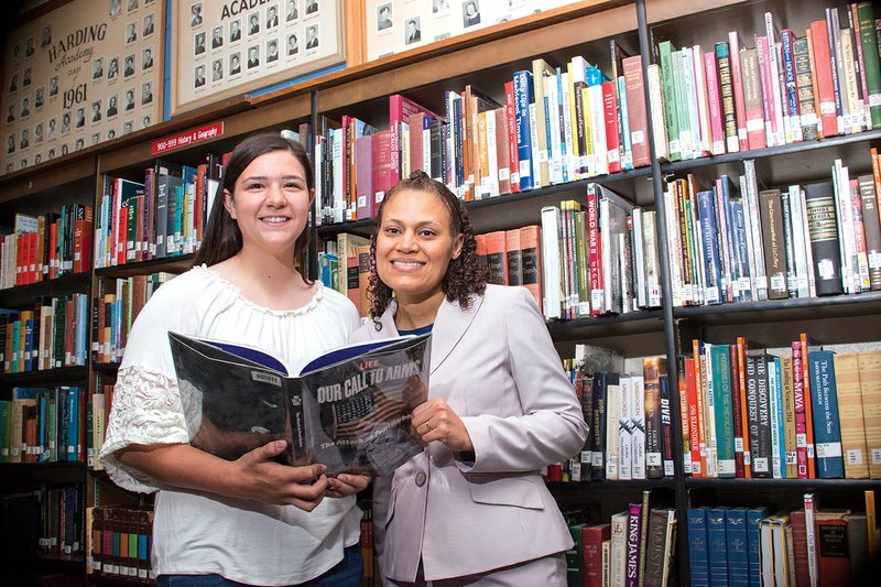 Harding Academy freshman Carson McFatridge, left, and Harding Academy social-studies teacher Angela Adams look at the Life magzine book Our Call to Arms: The Attack on Pearl Harbor in the school library. McFatridge and Adams have been invited to participate in educational programs this summer at the National WWII Museum in New Orleans.
