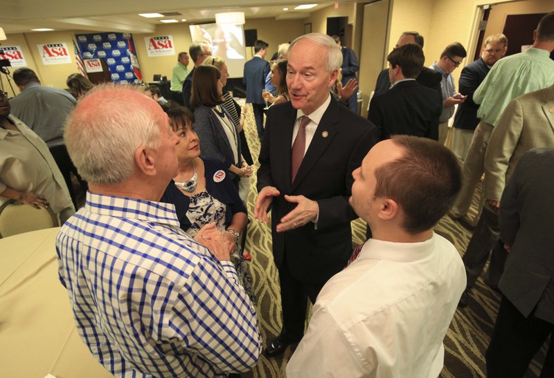 Governor Asa Hutchinson talks with supporters Tommy Mitchum (left) of Batesville, Vicki Kellar of Little Rock and John Yarbrough (right) of Ward on Tuesday night as he greets supporters at a watch party in Little Rock.
