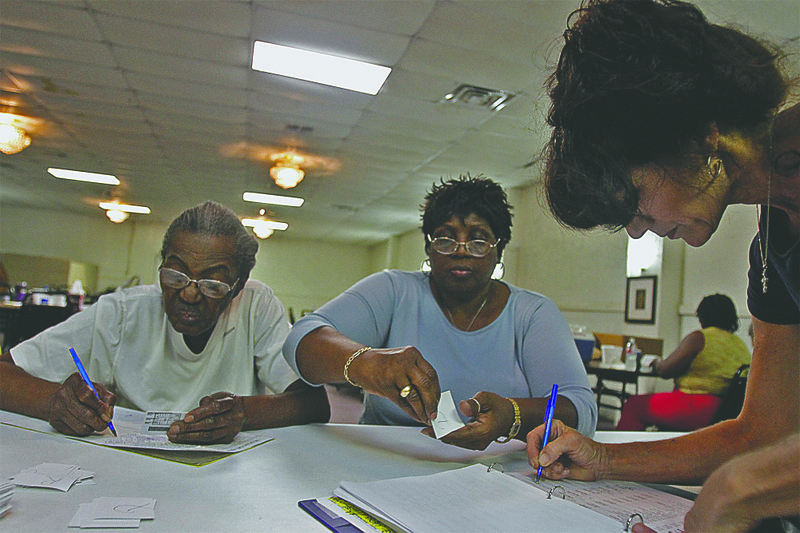 Ward 3 poll workers Joyce Williams, left, and Clevester Williams, center, watch as Teresa Golliher signs in to vote during the primary election Tuesday. Terrance Armstard/News-Times