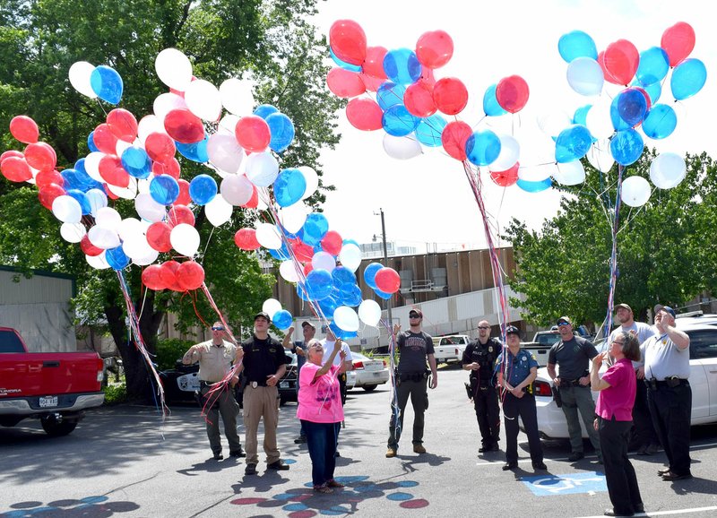 Westside Eagle Observer/MIKE ECKELS Up and away they fly as 150 balloons lift into the sky in remembrance of officers killed in the line of duty in the last 10 years. Officers and guests gathered at the Decatur Police Station May 15 to pay tribute to their fallen comrades.