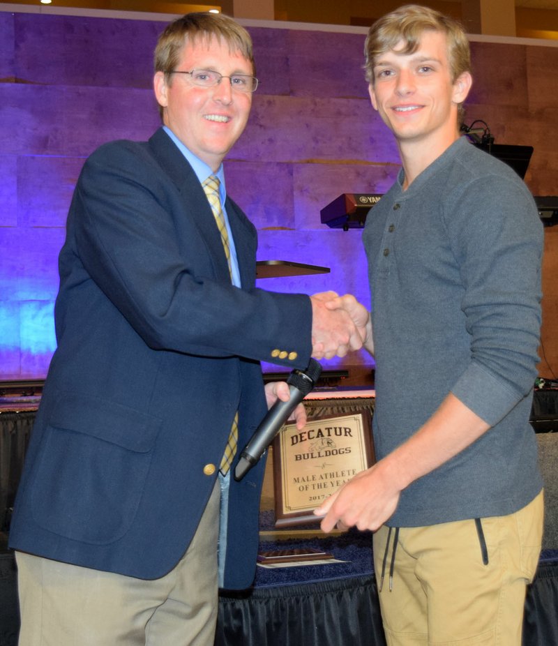 Westside Eagle Observer/MIKE ECKELS John Unger (left) presents the Male Athlete of the Year award to Taylor Haisman during the 2018 Decatur Sports Banquet at Decatur Assembly of God Church in Decatur May 14.